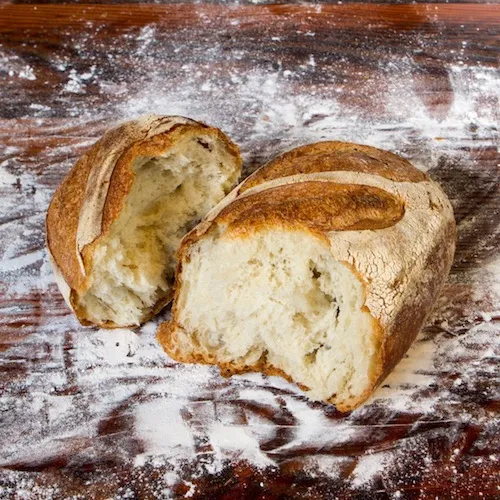 Baked bread sliced on barnwood table in flour at Middleground Farms